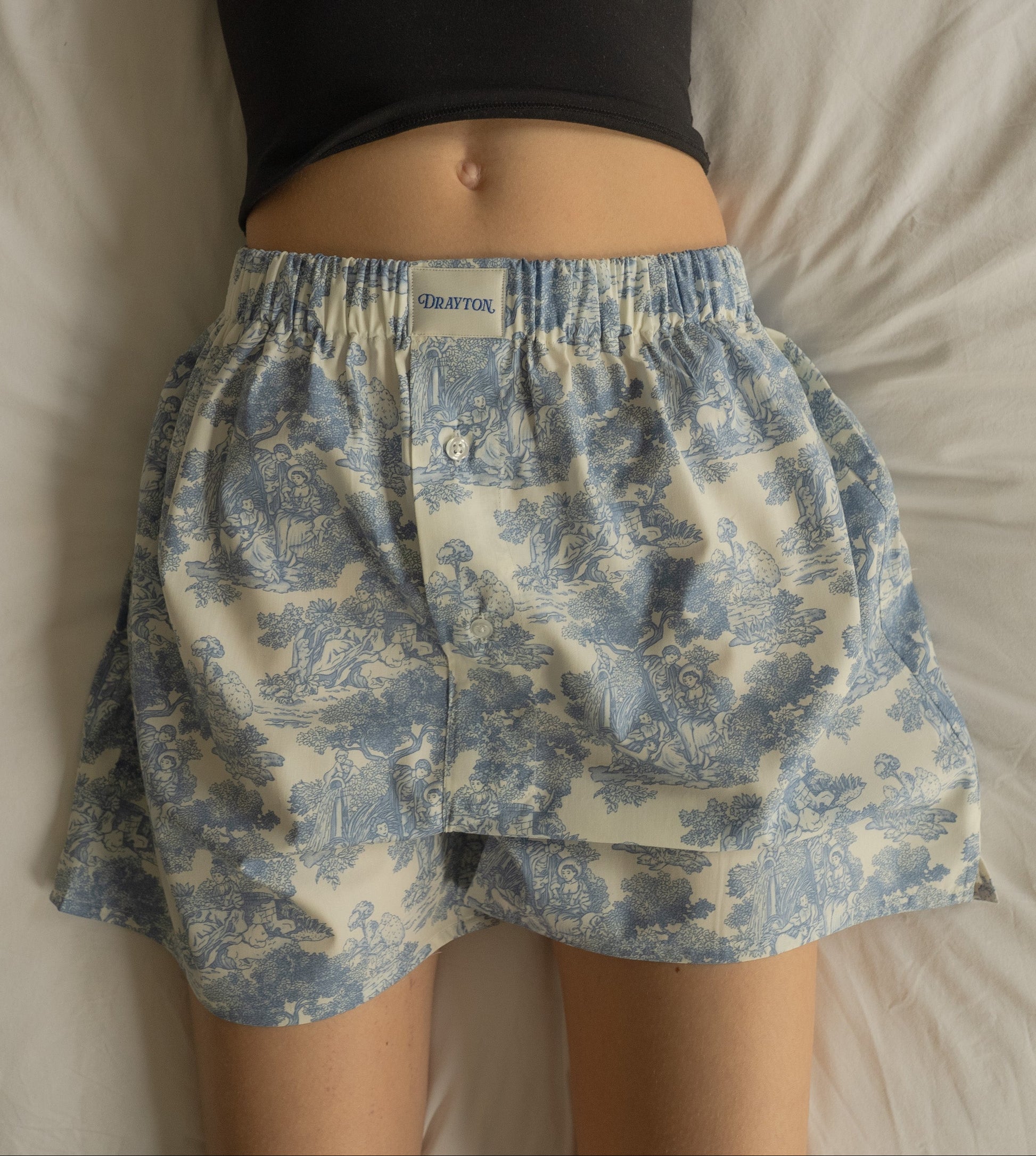Person wearing blue floral shorts on a plain background